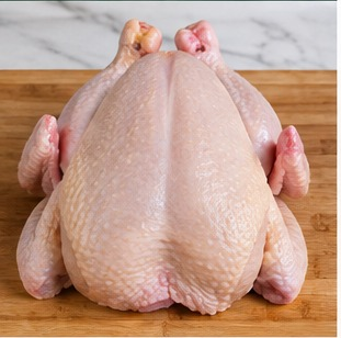 A whole raw chicken on a wooden board