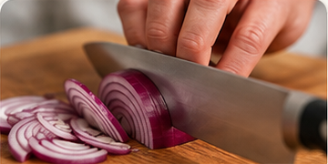 Slicing a red onion on a wooden cutting board