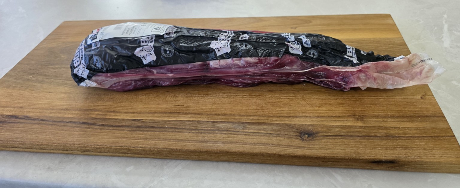 A whole eye fillet in its packaging on a chopping board